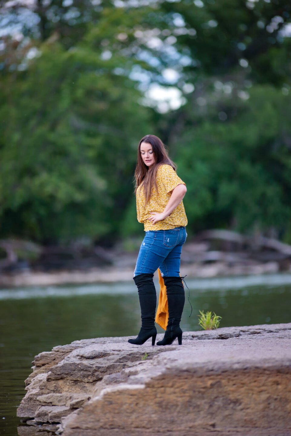 woman in jeans standing on a river bank