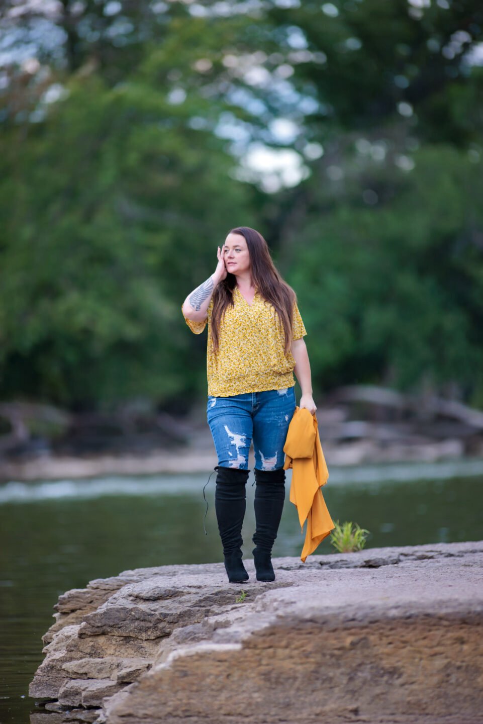 woman in jeans standing on a river bank