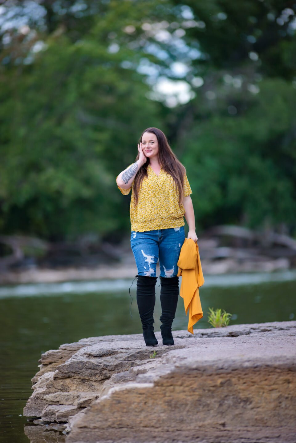 woman in jeans standing on a river bank