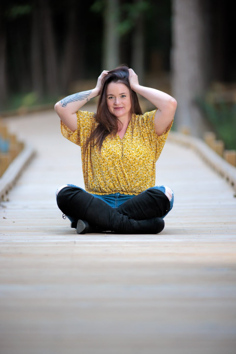Woman in jeans sitting on a boardwalk